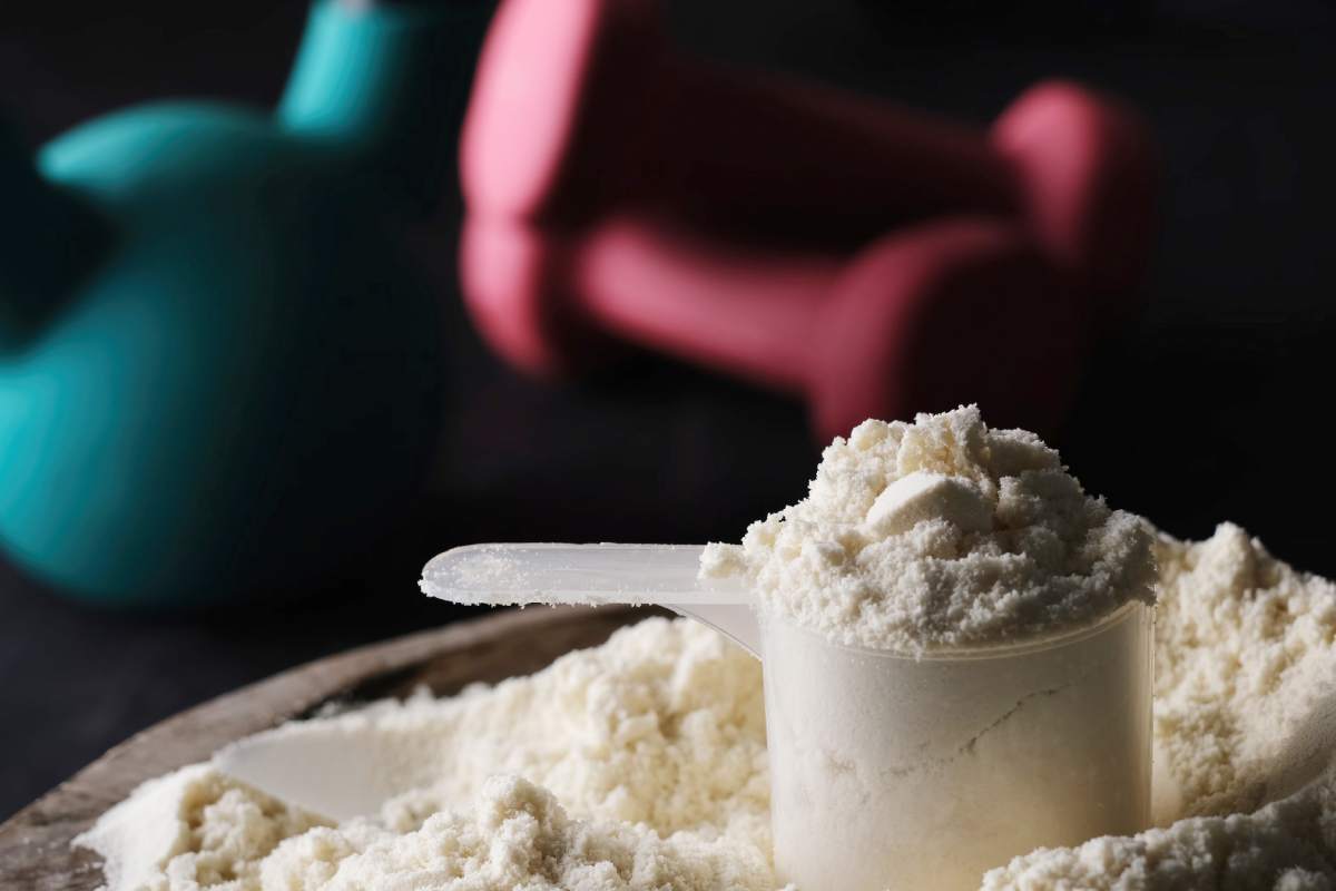 Measuring spoon with dry sports protein with sport equipment on a table