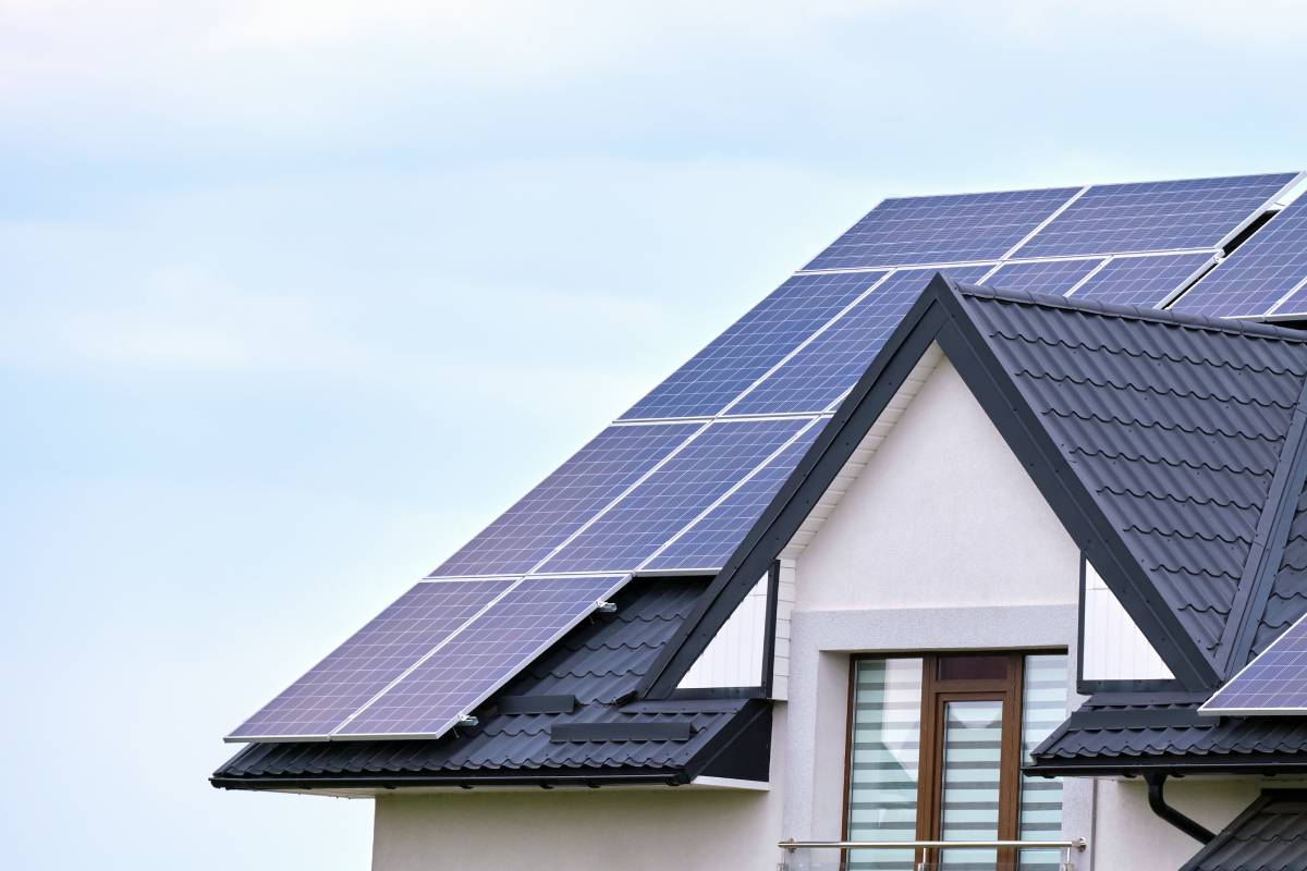 Residential house with rooftop covered with solar photovoltaic panels for producing of clean ecological electrical energy in suburban rural area. Concept of autonomous home