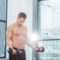 muscular shirtless sportsman exercising with dumbbells in gym