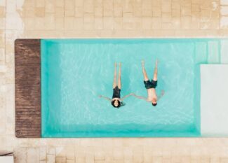 top view of couple lying in swimming pool and holding hands in Italy