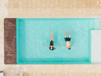 top view of couple lying in swimming pool and holding hands in Italy