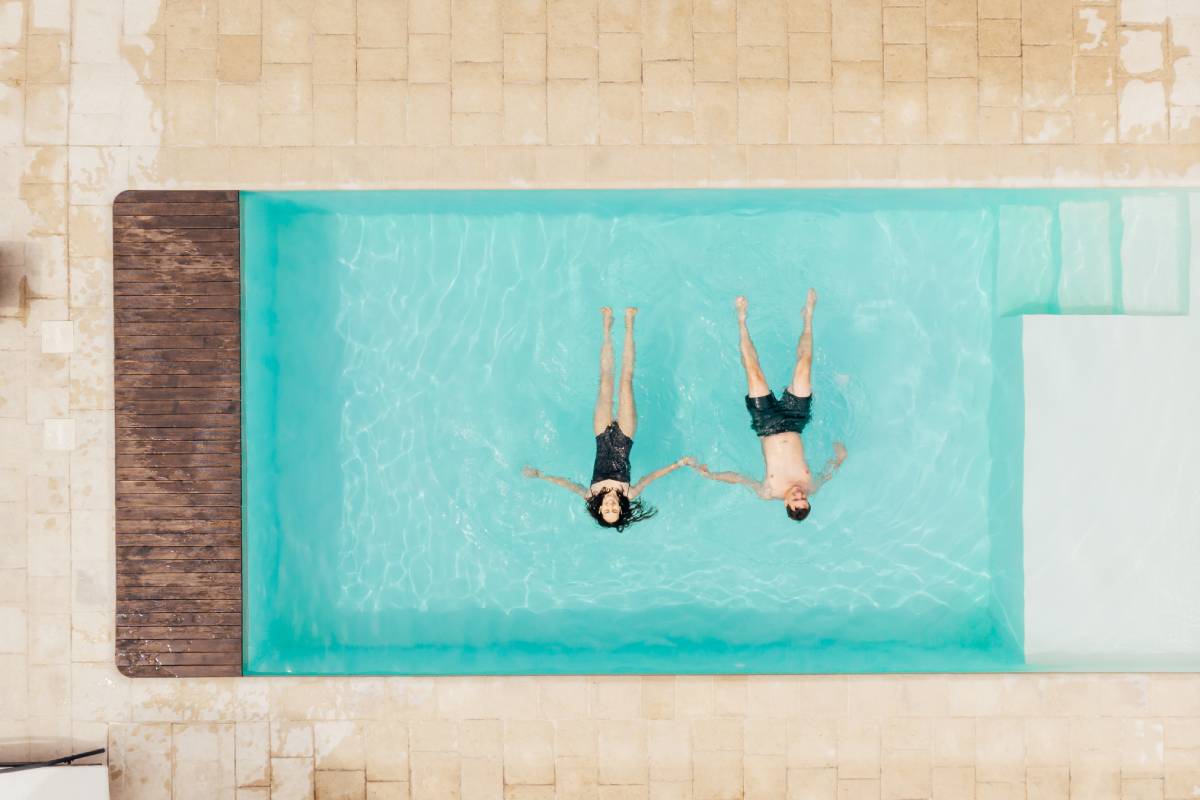top view of couple lying in swimming pool and holding hands in Italy